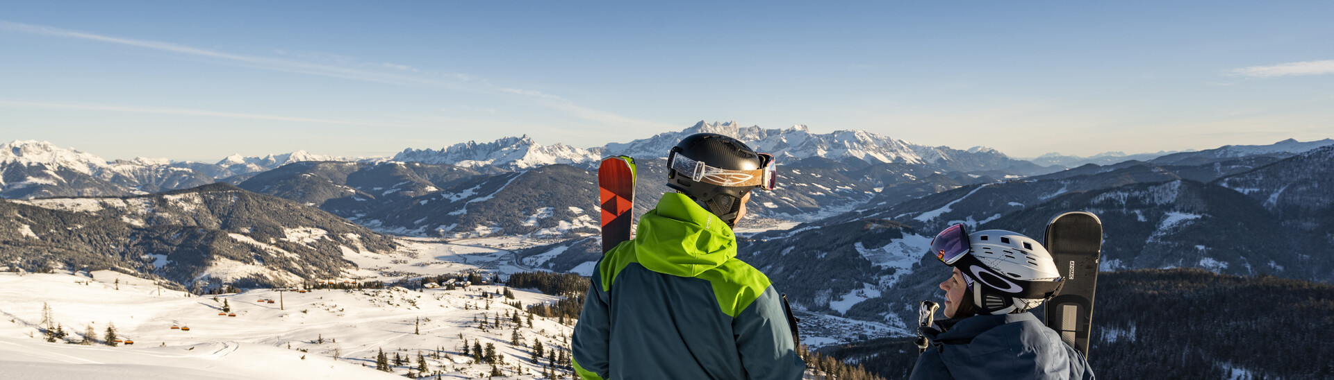 Panoramaaufnahme eines jungen Paares auf vor der winterlichen Berglandschaft von Snow Space Salzburg