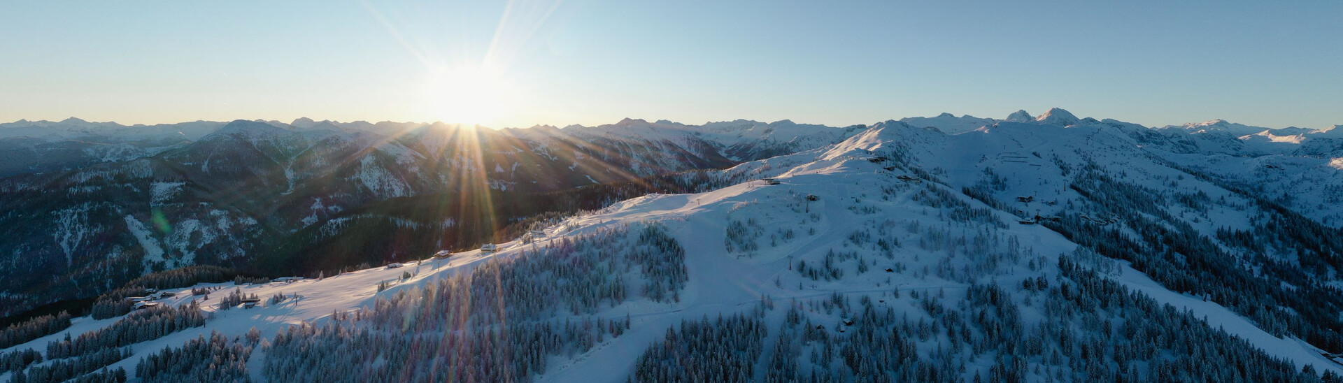 Panoramaaufnahme eines Sonnenaufgangs über der winterlichen Landschaft von Snow Space Salzburg